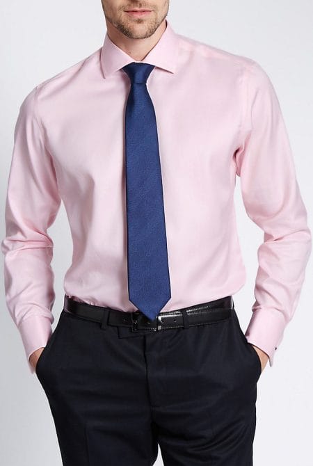 Front view of a custom-tailored men's pink oxford shirt, highlighting the extreme cutaway collar and double-pleated French cuffs.