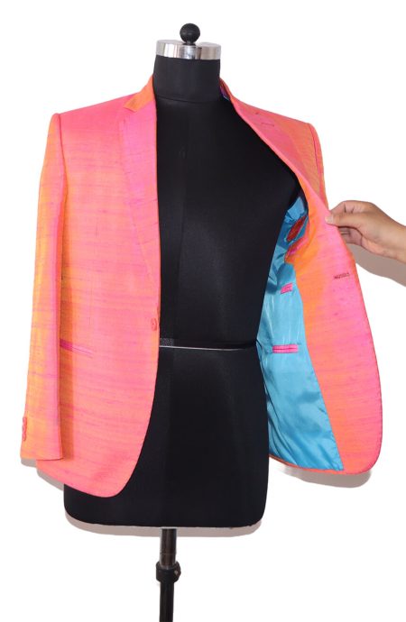 Men's blazer in 100% pink dupioni silk on a black mannequin stand, displaying the interior blue lining color and pockets.