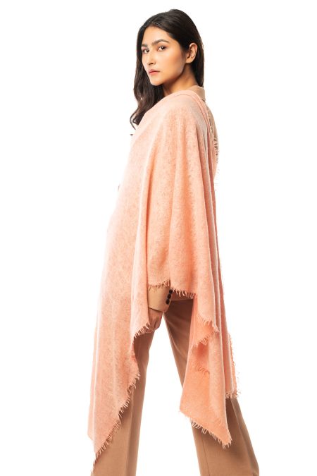 Model wearing a light salmon pink hand-knitted cashmere scarf, wrapped elegantly around the shoulders, showcasing the soft texture and natural drape of 100% pure cashmere.