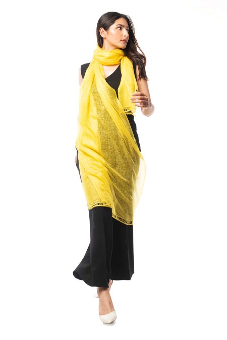 A woman in black pants and a vest walked elegantly with a yellow cashmere scarf draped around her neck.