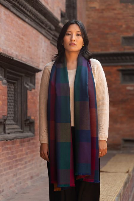 Model wearing the Kathmandu Twilight Check Cashmere Stole draped evenly on both sides over a cream sweater, showcasing the rich jewel-tone checkered pattern.