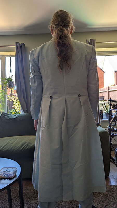 Reviewing the Structure: From the back, the customer can confirm the fit across the shoulder blades and the precise execution of the frock coat's pleating and waist buttons.