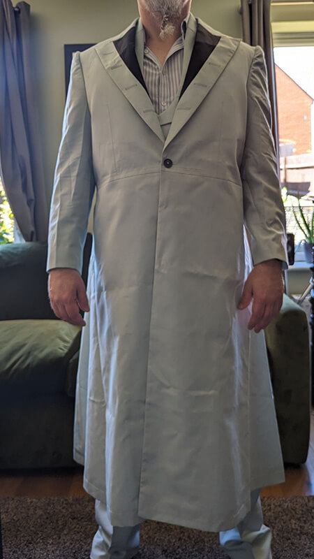 Assessing the Silhouette: The full front view allows the customer to check the drape of the coat, the shape of the dupioni silk lapels, and the overall fit across the chest and shoulders.