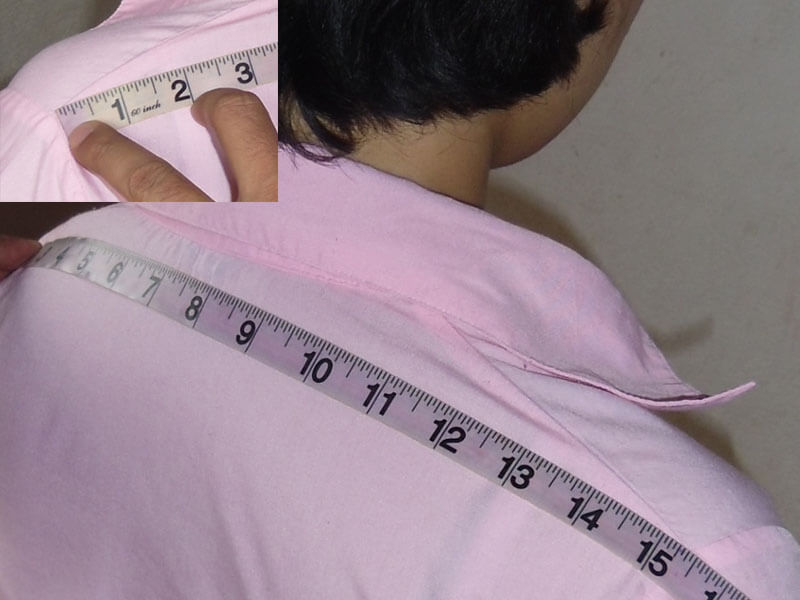 A detailed photo with an inset showing the shoulder-to-shoulder measurement for a custom women's blouse or jacket. The tape measure is laid across the back from one shoulder point to the other to achieve a precise fit across the shoulders.