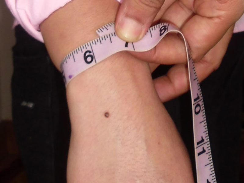 A guide to taking a wrist measurement for custom-fit shirt cuffs. The tape measure is wrapped around the wrist to ensure the cuff on a women's jacket, blouse or shirt is tailored for comfort and style.