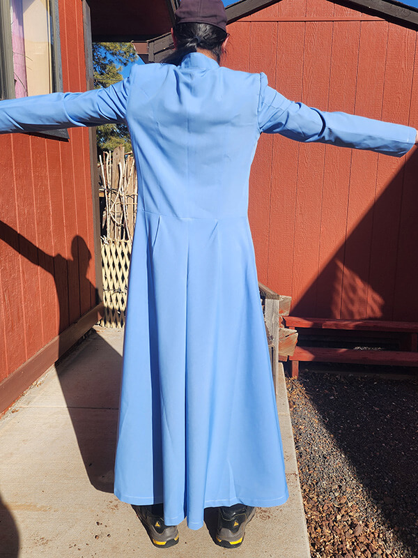 Full-length back view of the test coat for the custom-made Neo Leather Trench Coat. This set of image demonstrates the overall flow of the flared skirt and below-ankle length. The test coat is used to verify sizing and style before the final black leather version is crafted.