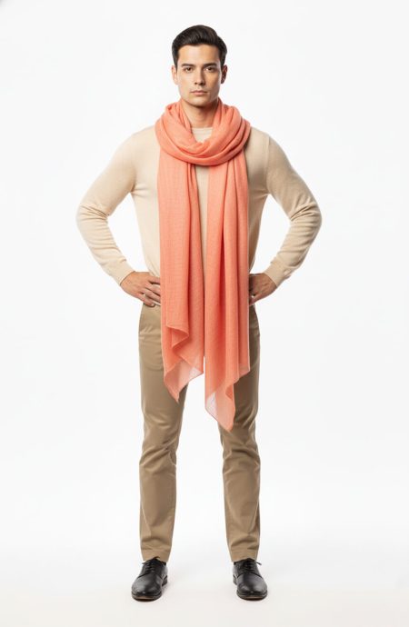 Man styling coral cashmere pashmina wrap as casual neck scarf with cream cardigan and beige trousers.