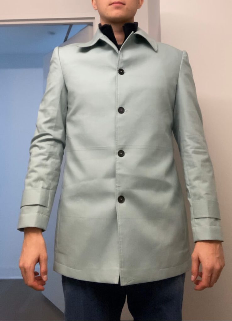 Front view of custom fitting toile for car coat showing preliminary garment before final herringbone tweed construction.