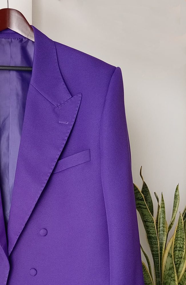 Close-up of the wide theatrical peak lapels and welt breast pocket on the bespoke 1989 Joker tailcoat, showing hand pick-stitching and double-breasted button placement, front detail view.