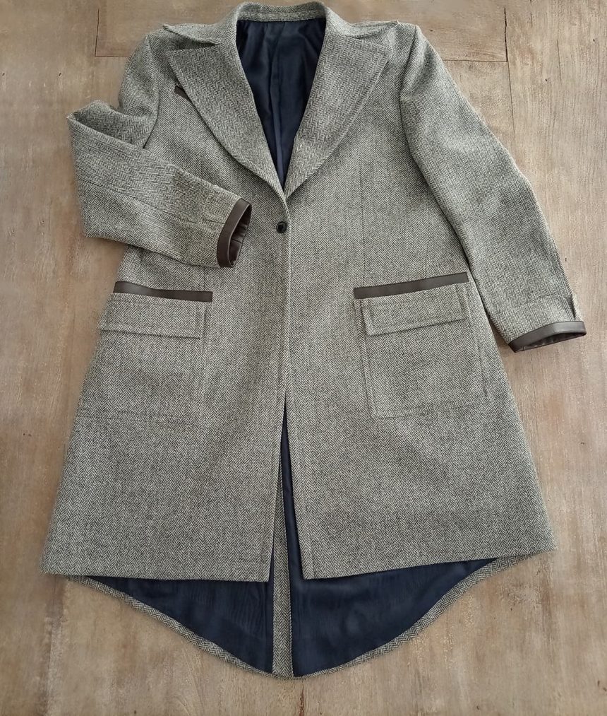 Lay-flat front view of fantasy-inspired grey herringbone tweed coat with leather trim details, combining cinematic wizard aesthetics with classic British tailoring.