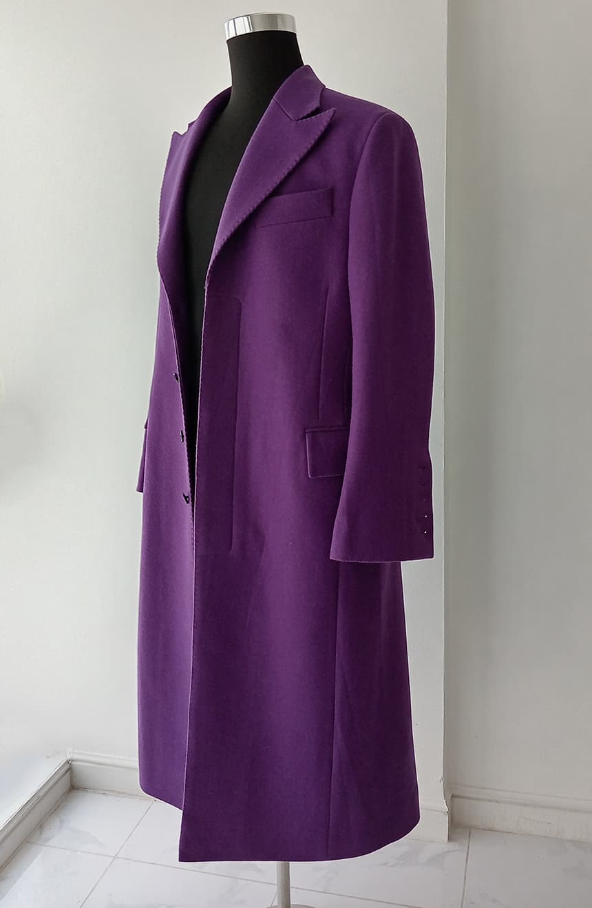 Side angle view of a Heath Ledger Joker inspired purple coat from The Dark Knight displayed on a mannequin. The coat features wide peak lapels, a fitted waist, 5-button styling, bell sleeves, and a long theatrical silhouette inspired by the Joker's signature look.