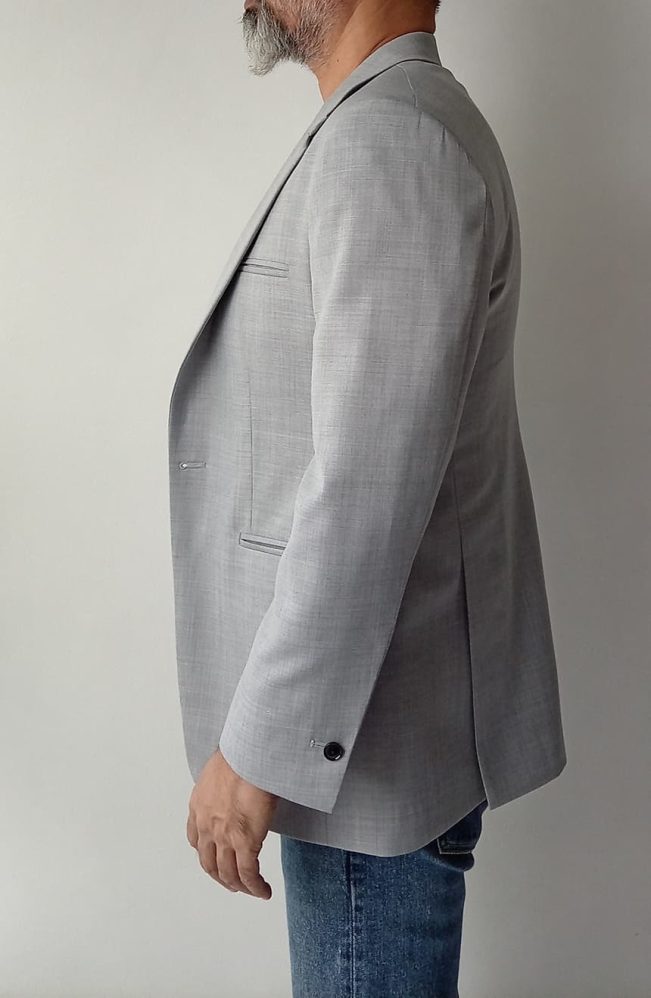 Men's Tom Cruise Collateral suit jacket in light grey worsted wool, clean side silhouette and rounded hem visible, left side view