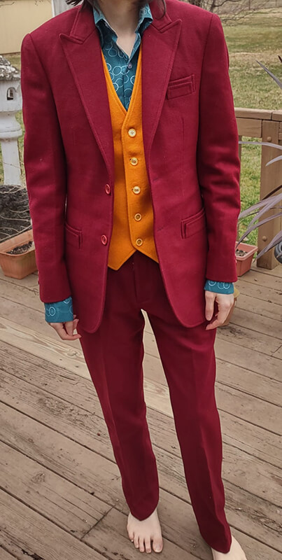 A customer modeling the final custom-made 2019 burgundy suit, displaying the rich texture of the Melton wool jacket, five-button gold yellow waistcoat, and matching trousers while standing outdoors.