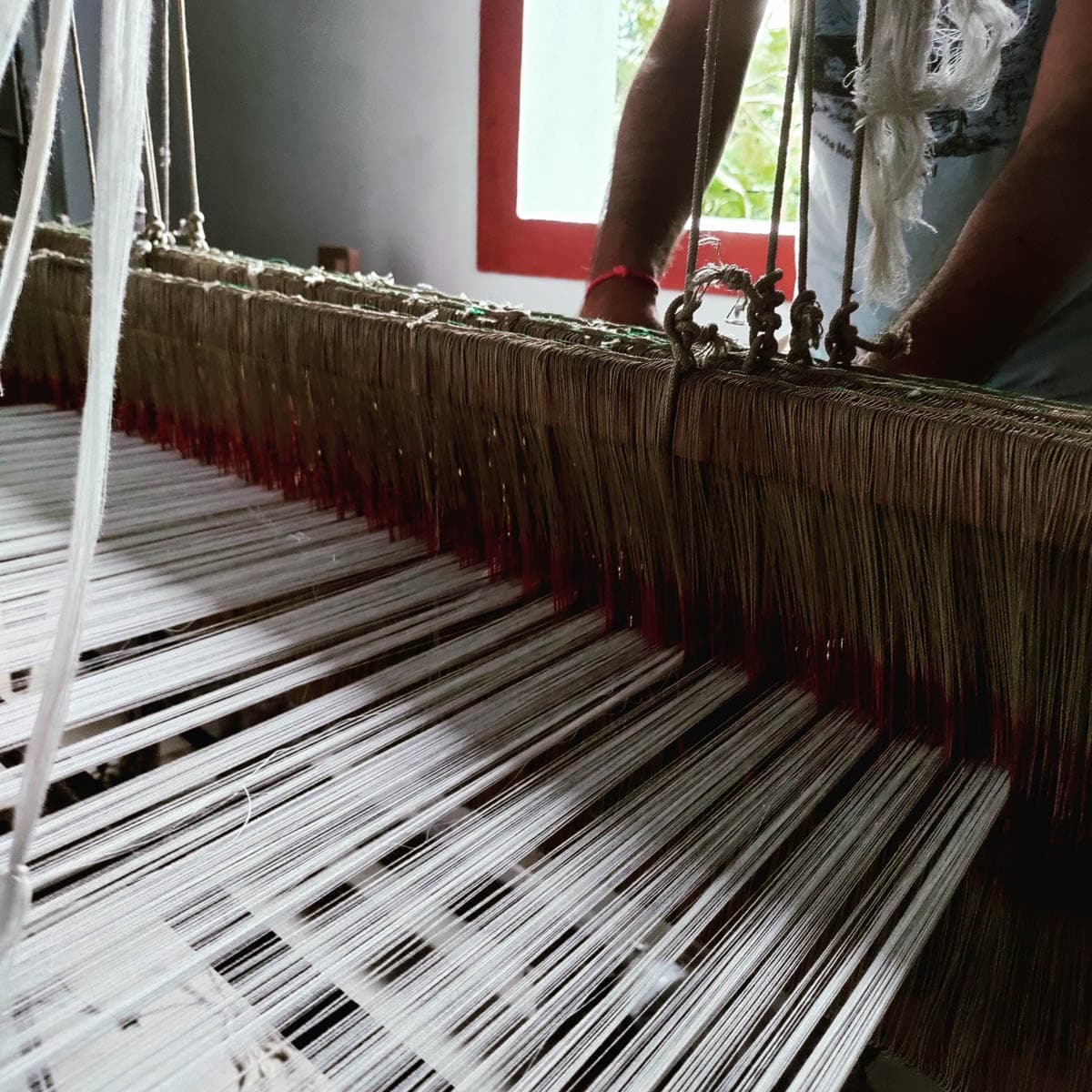 Master artisan handweaving cashmere scarf on a traditional wood handloom in Kathmandu workshop.